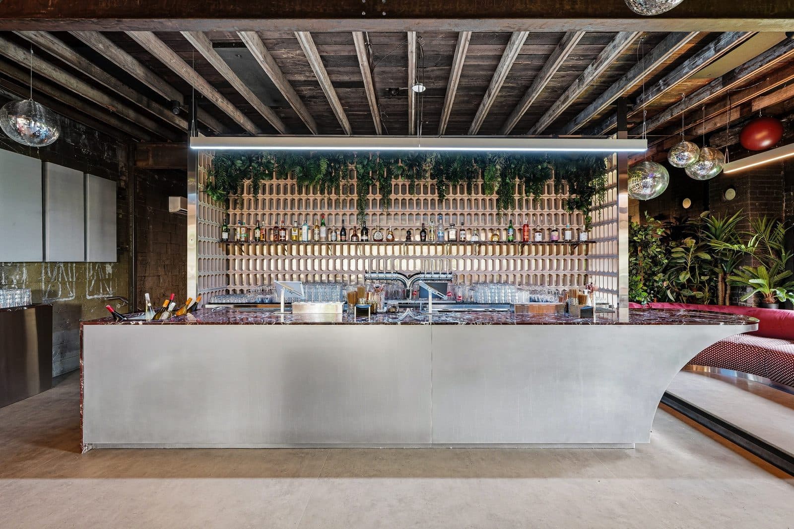 The bar at Riverside St-Henri before service, backed by a lit bottle wall under a timber ceiling