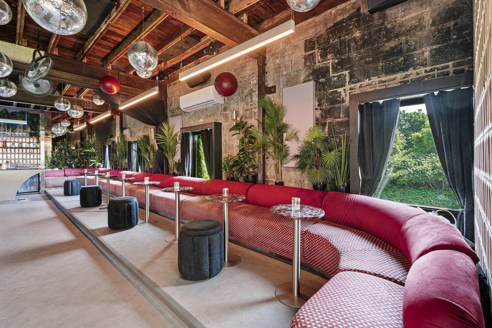 The lounge at Riverside St-Henri, the venue for Layover: mirror balls over a curved red banquette under exposed brick and timber